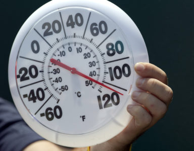 A television crew member hold a thermometer near the playing surface during the fifth inning of a baseball game between the Minnesota Twins and Kansas City Royals at Kauffman Stadium in Kansas City, Mo., Sunday, July 22, 2012. (AP Photo/Orlin Wagner)