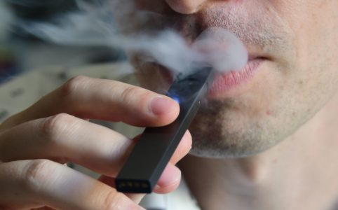 An illustration shows a man exhaling smoke from an electronic cigarette in Washington, DC on October 2, 2018. - In just three years, the electronic cigarette manufacturer Juul has swallowed the American market with its vaporettes in the shape of a USB key. Its success represents a public health dilemma for health authorities in the United States and elsewhere. (Photo by EVA HAMBACH / AFP) (Photo credit should read EVA HAMBACH/AFP/Getty Images)