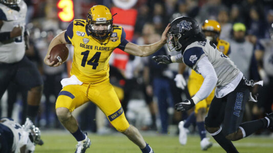 Dec 20, 2019; Frisco, TX, USA; Kent State Golden Flashes quarterback Dustin Crum (14) runs the ball against Utah State Aggies safety Troy Lefeged Jr. (3) during the first quarter during the Frisco Bowl at Toyota Stadium. Mandatory Credit: Tim Heitman-USA TODAY Sports
