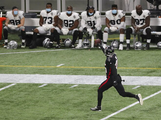 The Las Vegas Raiders bench watches as Atlanta Falcons linebacker Deion Jones intercepts a Derek Carr pass and returns it for a touchdown during the third quarter of an NFL football game on Sunday, Nov 29, 2020, in Atlanta. (Curtis Compton"/Atlanta Journal-Constitution via AP)