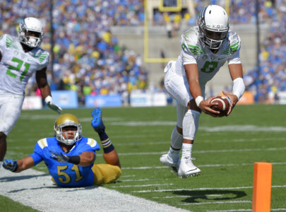 Oregon quarterback Marcus Mariota, right, dives in for a touchdown as UCLA linebacker Aaron Wallace, center, misses the tackle and running back Royce Freeman looks on during the first half of a NCAA college football game, Saturday, Oct. 11, 2014, in Pasadena, Calif. (AP Photo/Mark J. Terrill)
