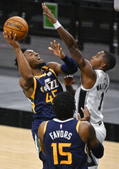 Utah Jazz's Donovan Mitchell (45) shoots against San Antonio Spurs' Lonnie Walker IV (1) as Jazz forward Derrick Favors looks on during the first half of an NBA basketball game, Sunday, Jan. 3, 2021, in San Antonio. (AP Photo/Darren Abate)