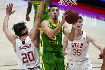 Oregon guard Chris Duarte, center, goes to the basket as Utah's Mikael Jantunen (20) and Branden Carlson (35) defend in the first half during an NCAA college basketball game Saturday, Jan. 9, 2021, in Salt Lake City. (AP Photo/Rick Bowmer)