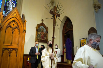 FILE - In this Sunday, March 28, 2021 file photo, altar server Samantha Holmes, of East Brookfield, Mass., center, carries a crucifix with palm leaves during a procession at the start of Palm Sunday Mass at Mary, Queen of the Rosary Parish in Spencer, Mass. For Christians across the United States, Easter services on Sunday will reflect an extra measure of joy as the nation experiences rising optimism after a year of pandemic. (AP Photo/Steven Senne)