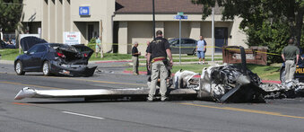 FILE - In this Sept. 12, 2017, file photo, an investigator looks at the wreckage of a small plane which struck a car, in the back ground, when it crashed into a neighborhood, in Roy, Utah. Utah has a new law requiring general aviation pilots with airplanes to carry at least $100,000 in liability insurance, inspired in part by the 2017 crash in Roy where a woman's car was hit. (AP Photo/Rick Bowmer, File)