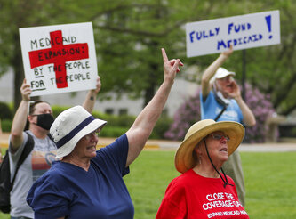 Maxine Horgan, left, and Barbara Nyden repeat the final chant of the Tuesday, April 27, 2021, Medicaid expansion rally at the Missouri State Capitol in Jefferson City. The Missouri Legislature is the latest statehouse fighting to undo voter-backed ballot measures. Missouri's GOP-led Senate this week voted against paying for voter-approved Medicaid expansion.  (Liv Paggiarino/The Jefferson City News-Tribune via AP)