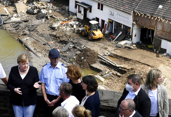 German Chancellor Angela Merkel, left, and the Governor of the German state of Rhineland-Palatinate, Malu Dreyer, rear third left, are seen on a bridge in Schuld, western Germany, Sunday, July 18, 2021 during their visit in the flood-ravaged areas to survey the damage and meet survivors. After days of extreme downpours causing devastating floods in Germany and other parts of western Europe the death toll has risen. (Christof Stache/Pool Photo via AP)