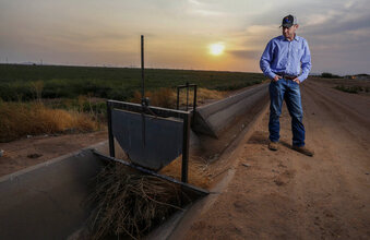 Will Thelander, a partner in his family’s farming business, looks into a dry irrigation canal on his property, Thursday, July 22, 2021, in Casa Grande, Ariz. The Colorado River has been a go-to source of water for cities, tribes and farmers in the U.S. West for decades. But climate change, drought and increased demand are taking a toll. The U.S. Bureau of Reclamation is expected to declare the first-ever mandatory cuts from the river for 2022. (AP Photo/Darryl Webb)
