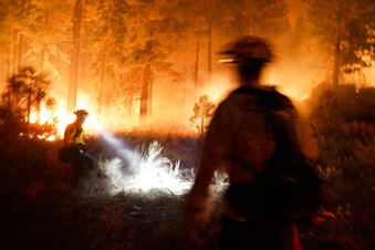 Two firefighters create a fuel break as the Caldor Fire burns near homes in South Lake Tahoe, Calif., Monday, Aug. 30, 2021. As the winds returned this week, the Caldor Fire roared over the Sierra crest and bore down on the southern end of Lake Tahoe. (AP Photo/Jae C. Hong)