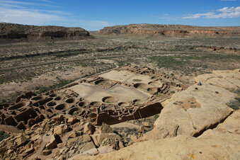 FILE - A hiker sits on a ledge above Pueblo Bonito, the largest archeological site at the Chaco Culture National Historical Park, in northwestern New Mexico, Aug. 28, 2021. The U.S. Interior Department says, Monday, Nov. 15,  oil and gas leasing within 10 miles of Chaco Culture National Historical Park in New Mexico will be prohibited for the next two years.  (AP Photo/Cedar Attanasio, File)