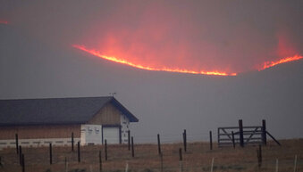 File—Flames rise from mountain ridges as a wildfire burns near a farmstead late Thursday, Oct. 22, 2020, near Granby, Colo. A bill is being introduced in the Colorado Legislature to create a $2-million pilot program to use cameras likely equipped with artificial intelligence technology in high-risk areas to help identify fires before they can burn out of control. (AP Photo/David Zalubowski, File)