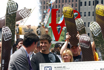 FILE - Skateboarders cheer as DC Shoes President Ken Block, center, wearing black shirt, smiles after pledging $1 million to support skateboarding in Philadelphia's LOVE Park on June 1, 2004. Block, the co-founder of DC Shoes and a pro rally driver who won multiple medals at the X-Games, died Monday, Jan. 2, 2023, in a snowmobiling accident near his home in Park City, Utah, authorities said. Block was 55. (AP Photo/Jacqueline Larma, File)