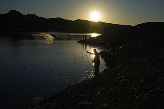 A fisherman throws a cast net along shore of Lake Mead at the Lake Mead National Recreation Area, Friday, Jan. 27, 2023, near Boulder City, Nev. Six western states that rely on water from the Colorado River have agreed on a plan to dramatically cut their use. California, the state with the largest allocation of water from the river, is the holdout. (AP Photo/John Locher)