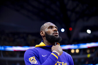 Los Angeles Lakers forward LeBron James peers at the American flag during the national anthem prior to the start of an NBA basketball game in Dallas, Sunday, Dec. 25, 2022. (AP Photo/Emil T. Lippe)