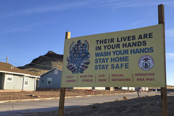 FILE - A sign urging safety measures during the coronavirus pandemic is displayed in Teesto, Ariz., on the Navajo Nation on Feb. 11, 2021. The Navajo Nation has rescinded a mask mandate that has been in effect since the early days of the coronavirus pandemic, officials announced Friday, Jan. 20, 2023, fulfilling a pledge that new tribal President Buu Nygren made while campaigning for the office. (AP Photo/Felicia Fonseca, File)