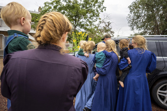 FILE - Family and followers of polygamous sect leader Samuel Bateman gather around as he calls from police custody following his arrest in Colorado City, Ariz., on Sept. 13, 2022. On March 24, 2023, federal charges were filed against Josephine Barlow Bistline, who is believed to be married to Bateman and is accused of sending threatening emails to child welfare workers in a bid to get her two daughters released from state foster care. (Trent Nelson/The Salt Lake Tribune via AP, File)