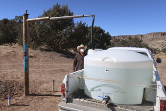 FILE - Phillip Yazzie waits for a water drum in the back of his pickup truck to be filled in Teesto, Ariz., on the Navajo Nation, on Feb. 11, 2021.  The Supreme Court has ruled against the Navajo Nation in a dispute involving water from the drought-stricken Colorado River. States that draw water from the river — Arizona, Nevada and Colorado — and water districts in California had urged the court to decide for them, and that's what the justices did in a 5-4 ruling. (AP Photo/Felicia Fonseca, File)