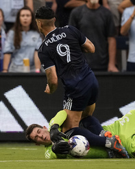 Real Salt Lake goalkeeper Gavin Beavers, bottom, blocks a goal attempt by Sporting Kansas City forward Alán Pulido (9) during the first half of an MLS soccer match Wednesday, July 12, 2023, in Kansas City, Kan. (AP Photo/Charlie Riedel)