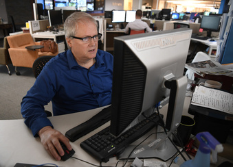 Reporter Kirk Mitchell at his desk in The Denver Post's newsroom in this photograph taken on August 23, 2017, in Denver. The Post's former crime reporter—who contributed to Pulitzer Prize-winning coverage of two mass shootings in Colorado—died Monday, Dec. 11, 2023, at the age of 64 in Lititz, Pa. (Andy Cross//The Denver Post via AP)