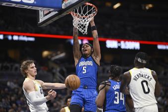 Orlando Magic forward Paolo Banchero (5) dunks between Utah Jazz forward Lauri Markkanen, left, and forward Taylor Hendricks during the first half of an NBA basketball game Thursday, Feb. 29, 2024, in Orlando, Fla. (AP Photo/Phelan M. Ebenhack)
