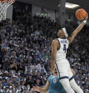 Utah State guard Ian Martinez (4) goes up to dunk the ball as New Mexico guard Jemarl Baker Jr. (0) defends during the first half of an NCAA college basketball game Saturday, March 9, 2024, in Logan, Utah. (Eli Lucero/The Herald Journal via AP)