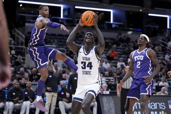 Utah State forward Kalifa Sakho (34) drives to the basket between TCU guard Avery Anderson III, left, and forward Emanuel Miller (2) in the first half of a first-round college basketball game in the NCAA Tournament, Friday, March 22, 2024, in Indianapolis. (AP Photo/Michael Conroy)