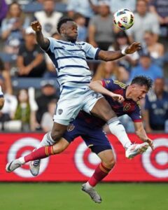 Sporting Kansas City attacker Willy Agada, left, and Real Salt Lake defender Bryan Oviedo battle for the ball during the first half of an MLS soccer match Wednesday, June 19, 2024, in Kansas City, Kan. (AP Photo/Charlie Riedel)