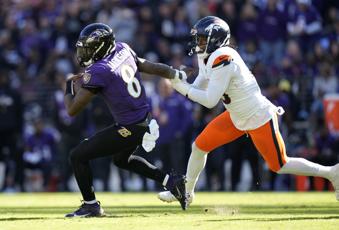 Baltimore Ravens quarterback Lamar Jackson, left, is pursued by Denver Broncos linebacker Baron Browning in the first half of an NFL football game Sunday, Nov. 3, 2024, in Baltimore. (AP Photo/Stephanie Scarbrough)