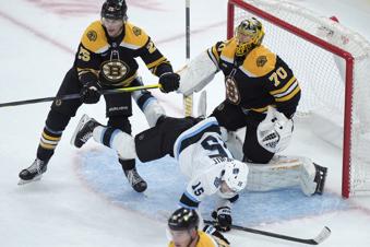 Utah Hockey Club center Alexander Kerfoot (15) tumbles in front of Boston Bruins defenseman Brandon Carlo (25) and goaltender Joonas Korpisalo (70) in the second period of an NHL hockey game, Thursday, Nov. 21, 2024, in Boston. (AP Photo/Steven Senne)