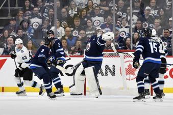 Winnipeg Jets' goaltender Connor Hellebuyck (37) reaches to grab a bouncing puck after a Utah Hockey Club shot during the second period of an NHL hockey game in Winnipeg, Manitoba, Tuesday Nov. 5, 2024. (Fred Greenslade/The Canadian Press via AP)