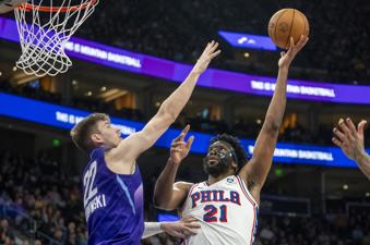 Philadelphia 76ers center Joel Embiid (21) shoots over Utah Jazz forward Kyle Filipowski (22) during the first half of an NBA basketball game Saturday, Dec. 28, 2024, in Salt Lake City. (AP Photo/Rick Egan)
