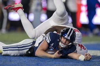 BYU quarterback Jake Retzlaff, bottom, slides into the end zone on a quarterback keeper, as Houston linebacker Jamal Morris, top, defends during the first half of an NCAA college football game Saturday, Nov. 30, 2024, in Provo. (AP Photo/Rick Egan)