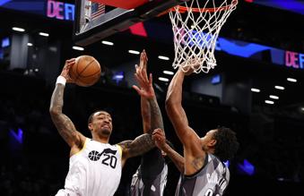 Utah Jazz forward John Collins (20) drives to the basket against Brooklyn Nets center Nic Claxton during the first half of an NBA basketball game, Saturday, Dec. 21, 2024, in New York. (AP Photo/Noah K. Murray)