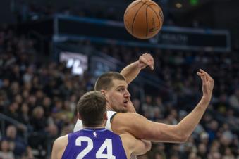 Denver Nuggets center Nikola Jokic, top, tosses a pass over his shoulder as Utah Jazz center Walker Kessler (24) defends during the first half of an NBA basketball game Monday, Dec. 30, 2024, in Salt Lake City. (AP Photo/Rick Egan)