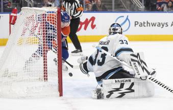 Utah Hockey Club goalie Jaxson Stauber (33) is scored against by Edmonton Oilers' Ryan Nugent-Hopkins (93) during the second period of an NHL hockey game in Edmonton, Alberta on Tuesday, Dec. 31, 2024. (Jason Franson/The Canadian Press via AP)