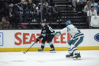 Utah Hockey Club center Barrett Hayton (27) moves the puck against San Jose Sharks defenseman Mario Ferraro (38) during the first period of an NHL hockey game Friday, Jan. 10, 2025, in Salt Lake City. (AP Photo/Melissa Majchrzak)