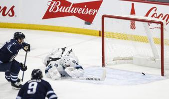 Utah Hockey Club goaltender Connor Ingram, right, who got stuck behind his net, dives to try save a shot by Winnipeg Jets' David Gustafsson, upper left, during second-period NHL hockey game action in Winnipeg, Manitoba, Friday, Jan. 24, 2025. (John Woods/The Canadian Press via AP)
