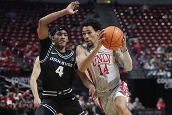 UNLV guard Jailen Bedford (14) drives the ball against Utah State guard Ian Martinez (4) during the first half of an NCAA college basketball game, Wednesday, Jan. 15, 2025, in Las Vegas. (AP Photo/Lucas Peltier)