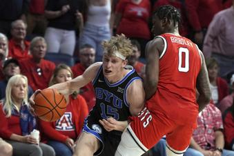 BYU forward Richie Saunders (15) drives against Arizona guard Jaden Bradley (0) during the first half of an NCAA college basketball game, Saturday, Feb. 22, 2025, in Tucson, Ariz. (AP Photo/Rick Scuteri)