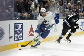 Vancouver Canucks left wing Kiefer Sherwood (44) moves the puck against Utah Hockey Club right wing Dylan Guenther (11) the second period of an NHL hockey game, Sunday, Feb. 23, 2025, in Salt Lake City. (AP Photo/Melissa Majchrzak)