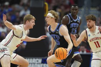 Brigham Young forward Richie Saunders, center, drives between Wisconsin forward Steven Crowl, left, and guard Max Klesmit during the first half in the second round of the NCAA college basketball tournament Saturday, March 22, 2025, in Denver. (AP Photo/David Zalubowski)