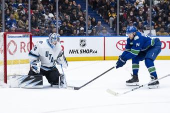 Utah Hockey Club goaltender Karel Vejmelka (70) stops Vancouver Canucks' Jake DeBrusk (74) during the third period of an NHL hockey game in Vancouver, British Columbia, Sunday, March 16, 2025. (Ethan Cairns/The Canadian Press via AP)