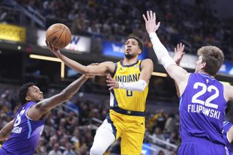 Indiana Pacers guard Tyrese Haliburton (0) is fouled as he shoots between Utah Jazz forward Brice Sensabaugh (28) and forward Kyle Filipowski (22) during the first half of an NBA basketball game in Indianapolis, Friday, April 4, 2025. (AP Photo/Michael Conroy)