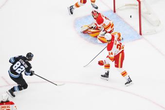 Utah Hockey Club center Kevin Stenlund (82) shoots and scores a goal past Calgary Flames goaltender Dustin Wolf (32) during the first period of an NHL hockey game, Tuesday, April 1, 2025, in Salt Lake City. (AP Photo/Tyler Tate)