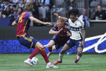 Vancouver Whitecaps' Jayden Nelson, back right, is shoved off the ball by Real Salt Lake's Justen Glad, back left, as Philip Quinton, front left, watches during the second half of an MLS soccer match, in Vancouver, on Saturday, May 3, 2025. (Darryl Dyck/The Canadian Press via AP)